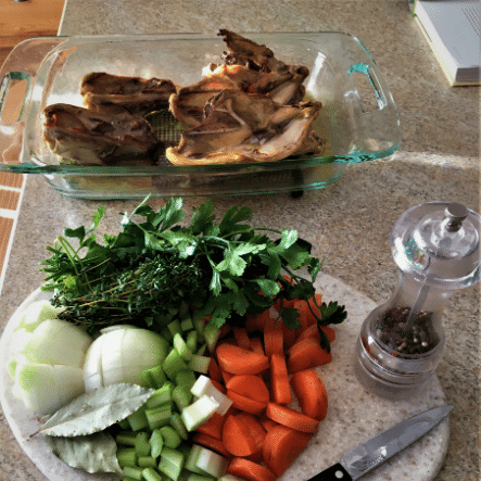 Raw vegetables and cooked chicken bones for making homemade chicken broth.