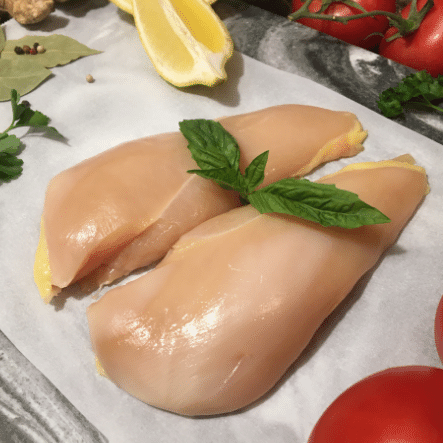 Raw chicken breast dressed with a sprig of basil.