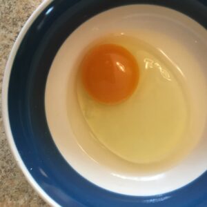 Soy-free pasture-raised egg, cracked into a bowl.